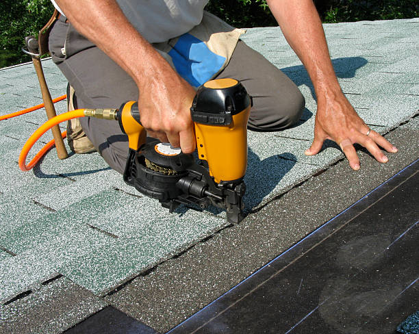 man using nail gun to apply asphalt shingles to a roof